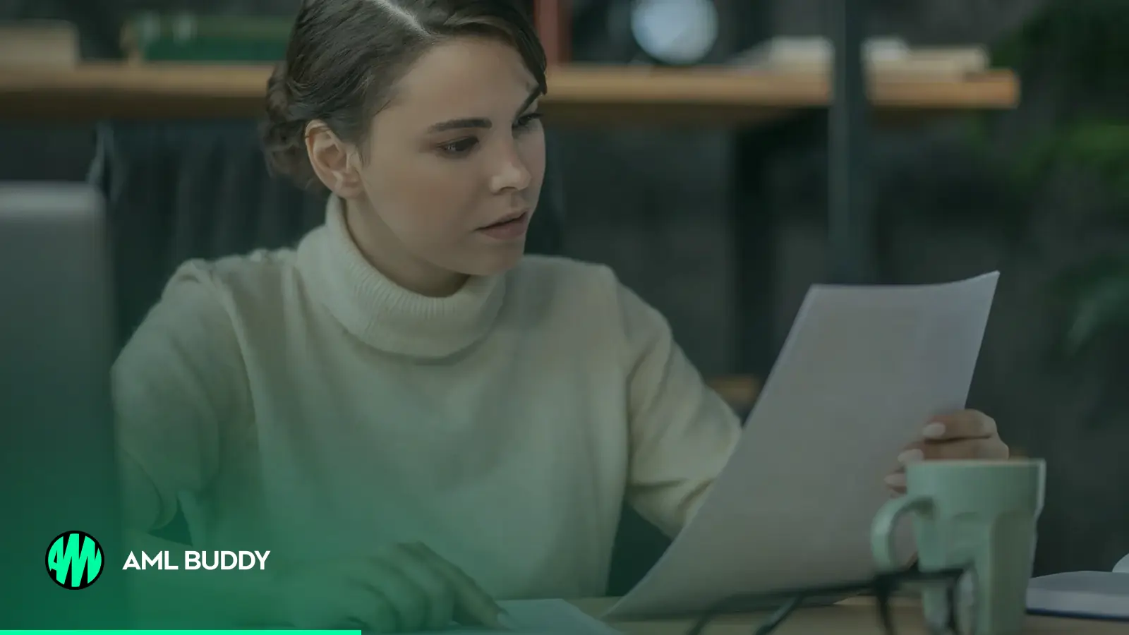A woman at a desk reading through printed documents next to a laptop