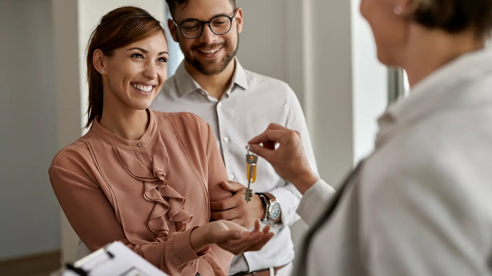 A couple receiving the keys to their new home from an estate agent